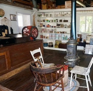The museum's general store exhibit with a wooden counter, a red coffee grinder, a pot-bellied stove and shelves of vintage goods.