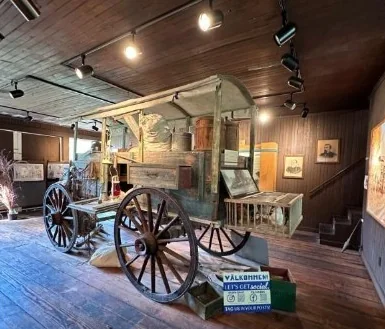 The museum's restored wooden Huckster wagon on display under gallery lights.